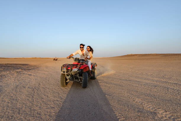 couple having fun while driving quad bike in the desert. 
