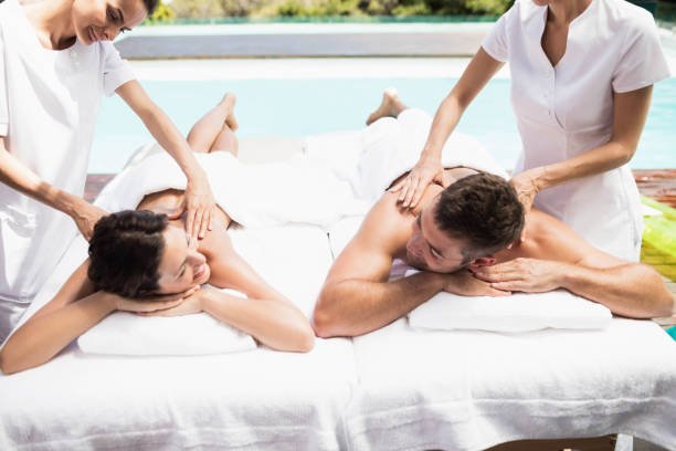 Relaxed young couple receiving a back massage from masseur in a spa